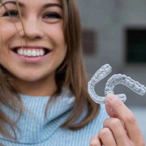 adult holds aligners as she talks about Clear aligners vs braces