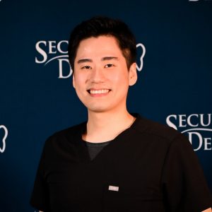 Head and shoulders image of Dr. Daniel Kang in front of a Secure Dental backdrop
