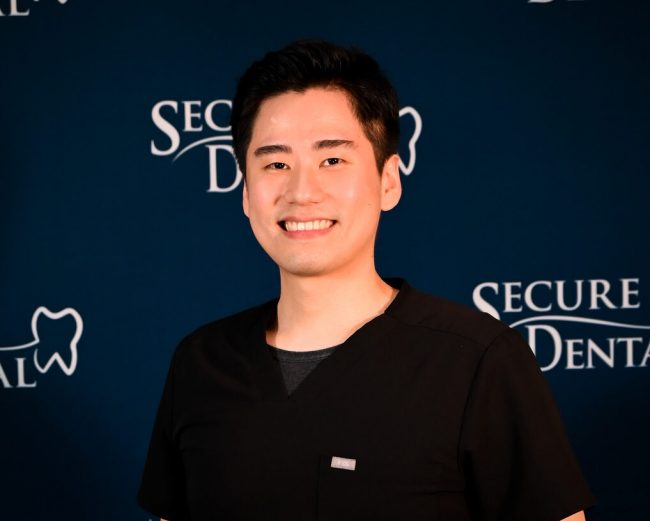 Head and shoulders image of Dr. Daniel Kang in front of a Secure Dental backdrop