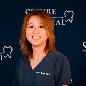 Dr. Lunan Shao, general dentist smiling for headshot wearing navy scrubs