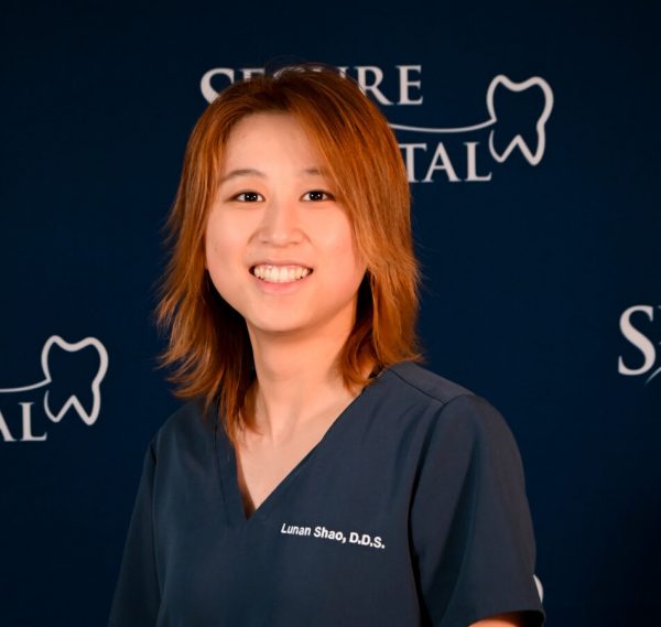 Dr. Lunan Shao, general dentist smiling for headshot wearing navy scrubs