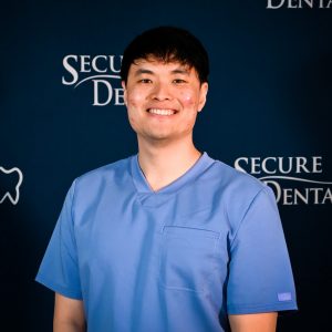Dr. Jonathan Phen, professional dentist with a warm smile and blue scrubs