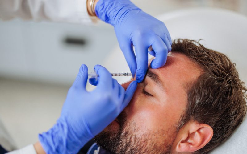 A female dermatologist is performing a procedure on a patient, injecting treatment into the scalp with precision and care, highlighting the specialized work of medical professionals